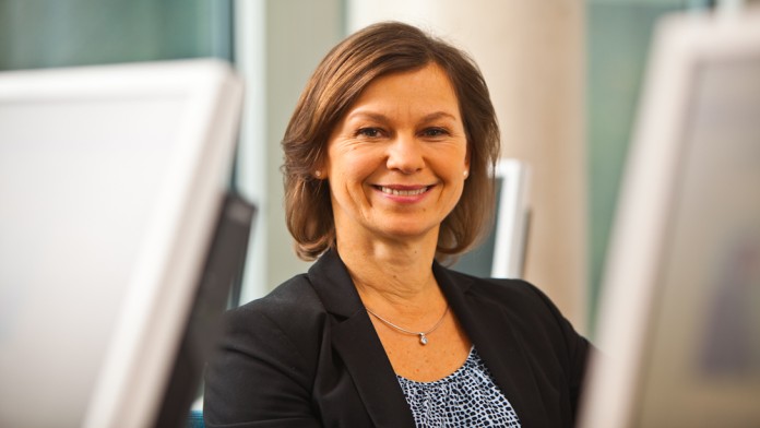 Eine Frau zwischen diversen PC-Monitoren
