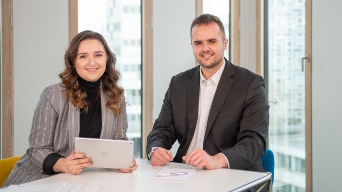 eine junge Mitarbeiterin und ihr Kollege an einem Besprechungstisch