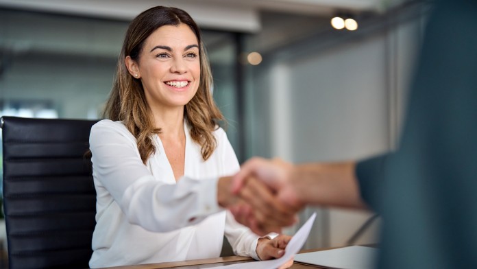 Happy mid aged business woman manager handshaking at office meeting.