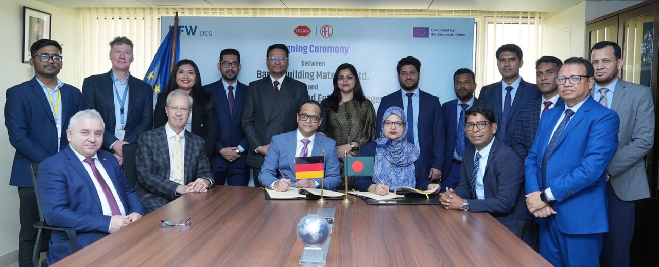 Mehrere Menschen stehen um einen Konferenztisch nach einer Vertragsunterzeichnung