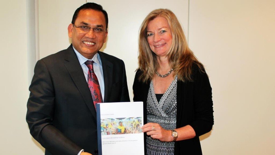 Ein Geschäftsmann aus Bangladesch und eine europäische Geschäftsfrau halten eine Studie in den Händen.