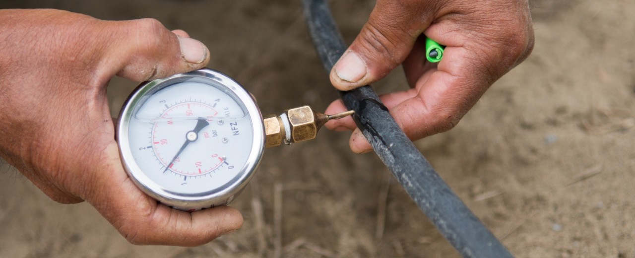 Ressourcen schonen - ein Mitarbeiter misst den Wasserdruck bei einem Bewässerungsschlau.