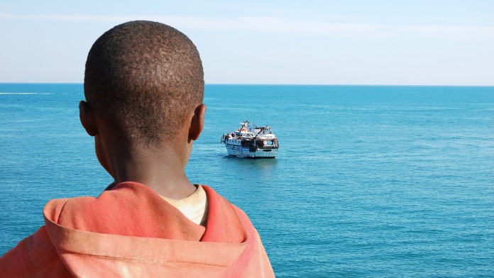 An African child as she watches a barge with his friends on board